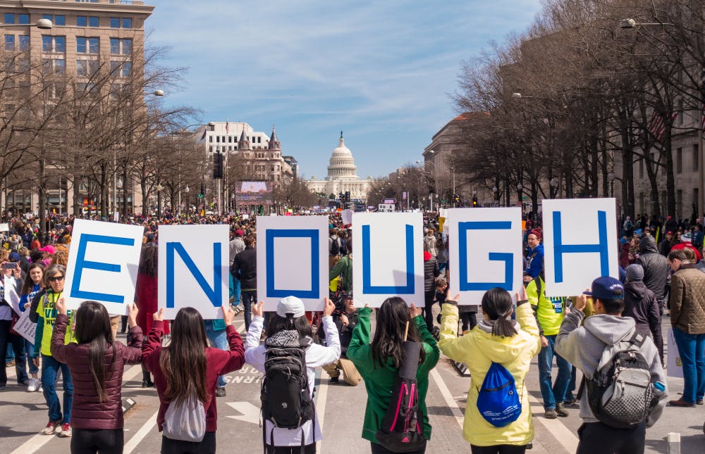 March for Our Lives protesters hold sign saying Enough