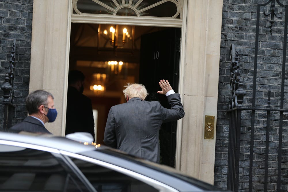 Boris Johnson waves as he walks into Downing Street with his back to the camera