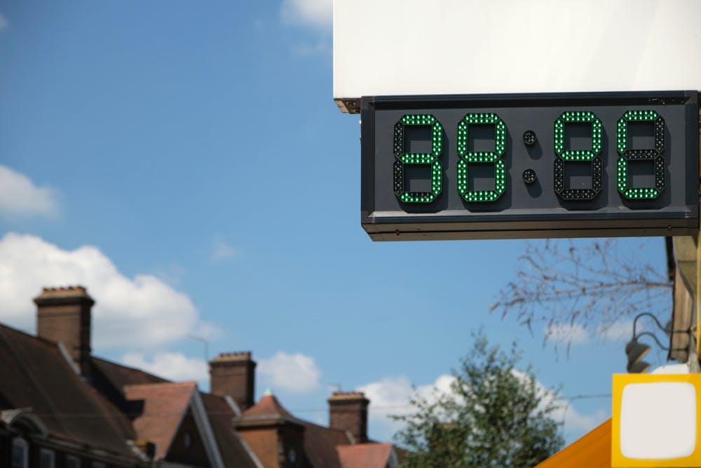 digital thermometer reads 38 degrees against a backdrop of homes and a blue sky in London