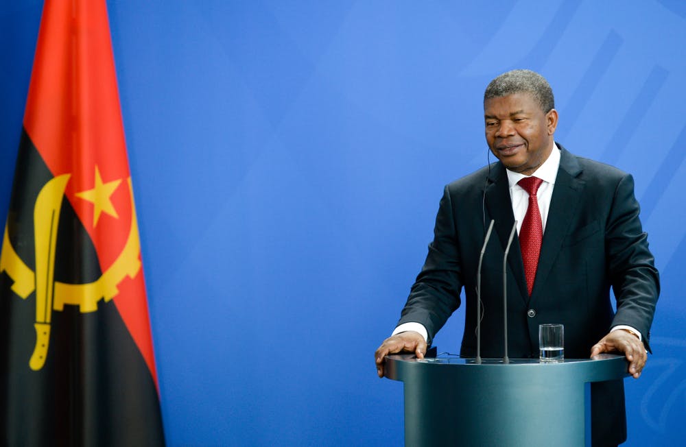 Angolan President Joao Lourenco stands at a podium next to an Angolan flag
