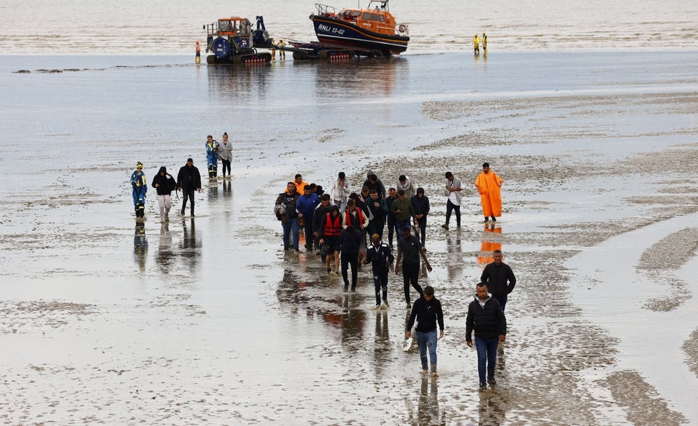 Migrants and rescue staff on a beach in Dungeness, Kent