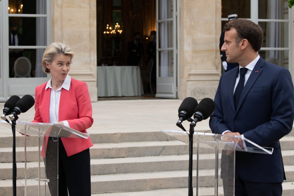 Ursula von der Leyen and Emmanuel Macron stand at podiums
