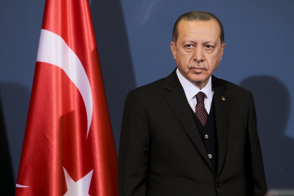 Recep Tayyip Erdogan stands in front of a Turkish flag