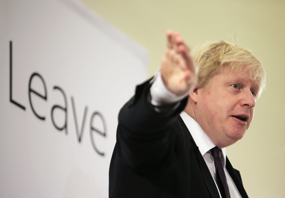 Boris Johnson stands in front of a poster reading Leave