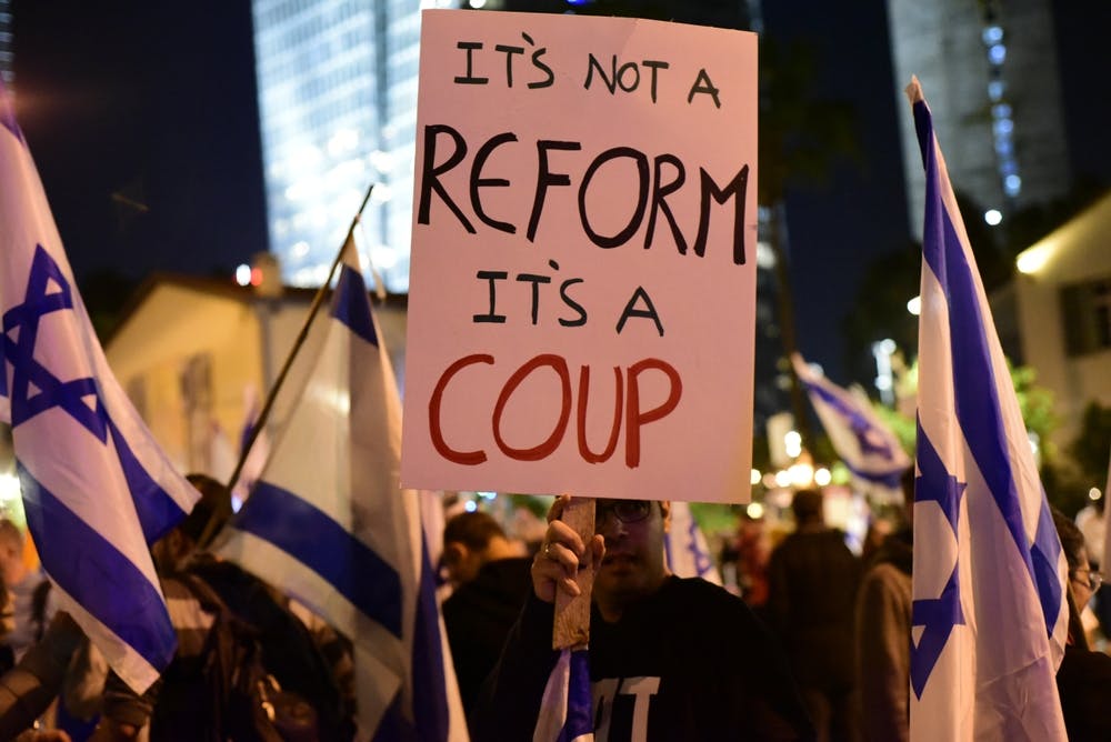 Israeli protesters hold a sign reading It's not a reform It's a coup