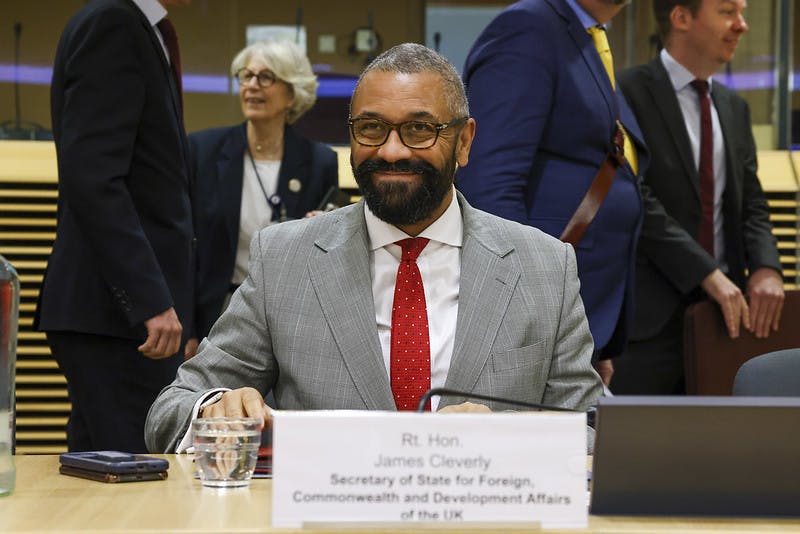 James Cleverly sits at a table with a name badge in front of him