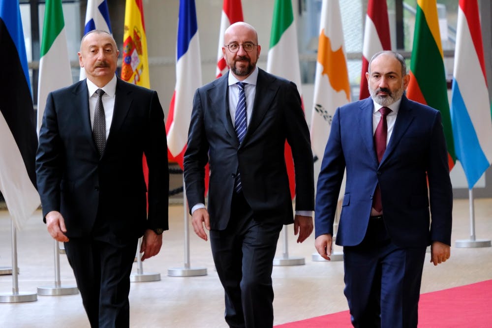 Ilham Aliyev, Charles Michel and Nikol Pashinyan walk together in front of flags
