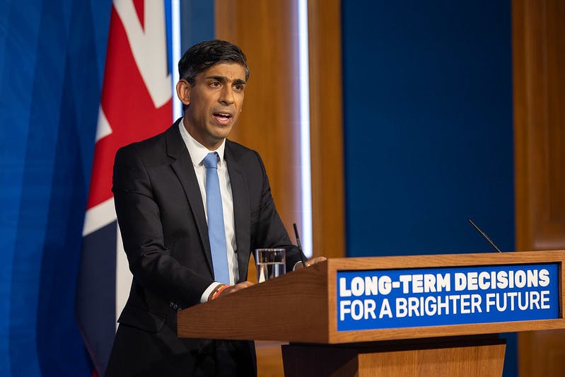 Rishi Sunak stands at a podium with a sign that reads Long-Term Decisions for a Brighter Future