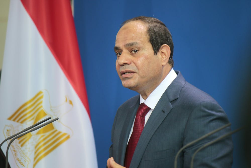 Fattah El-Sisi stands in front of an Egyptian flag