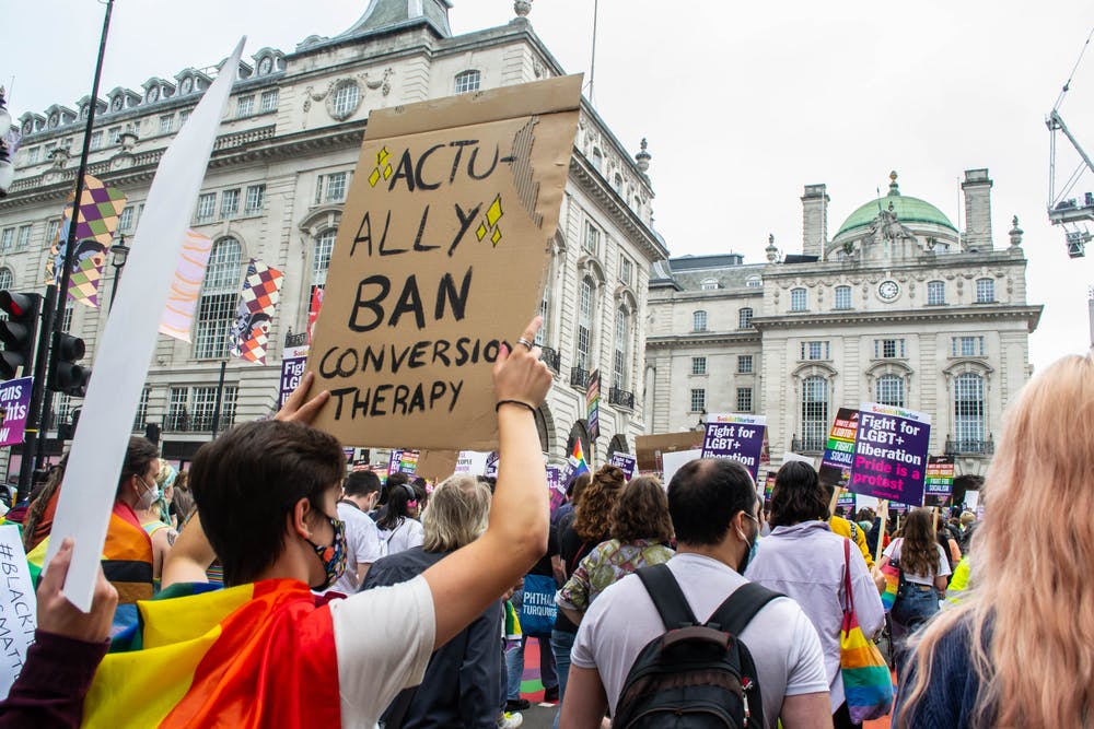Protester in London holds sign reading "Actually ban conversion therapy"