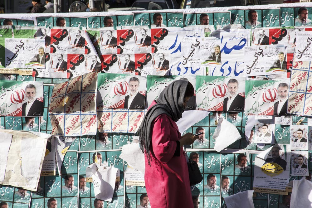 Woman walks in front of election campaign posters in Iran