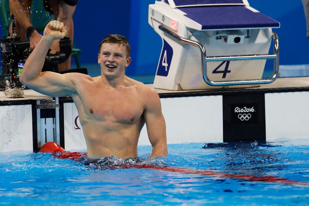 Adam Peaty raises an arm in celebration in the pool