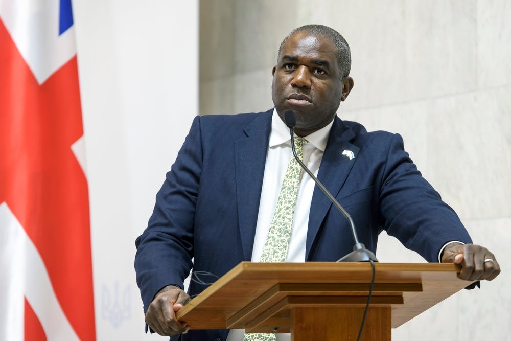 David Lammy stands at a lectern in front of a UK flag