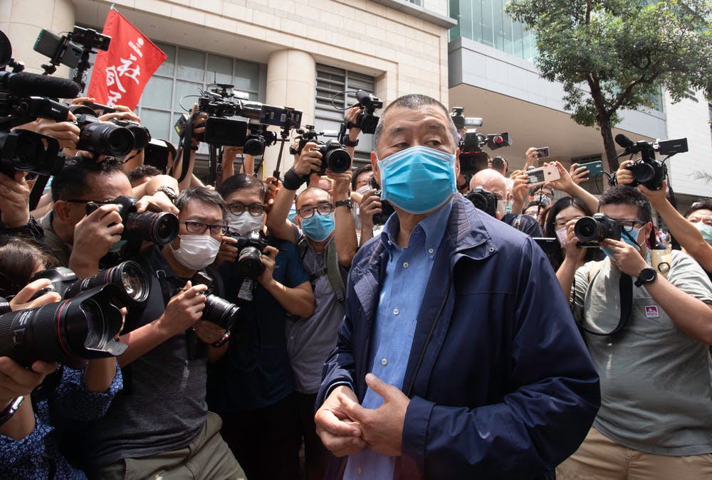 Jimmy Lai stands outside of a court surrounded by journalists and photographers
