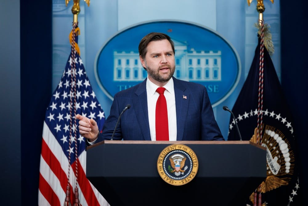 JD Vance speaks at a podium in front of flags