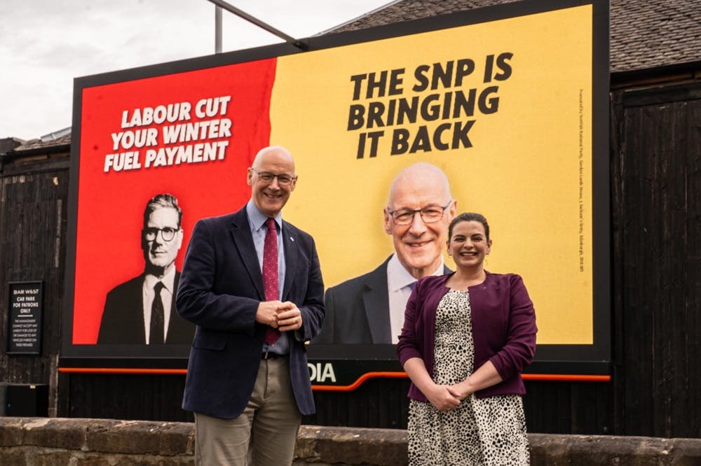 John Swinney and Katy Loudon stand in front of SNP campaign posters