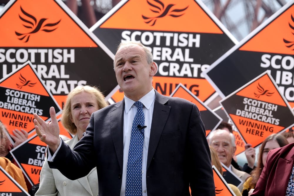 Ed Davey stands in front of orange signs reading Scottish Liberal Democrats