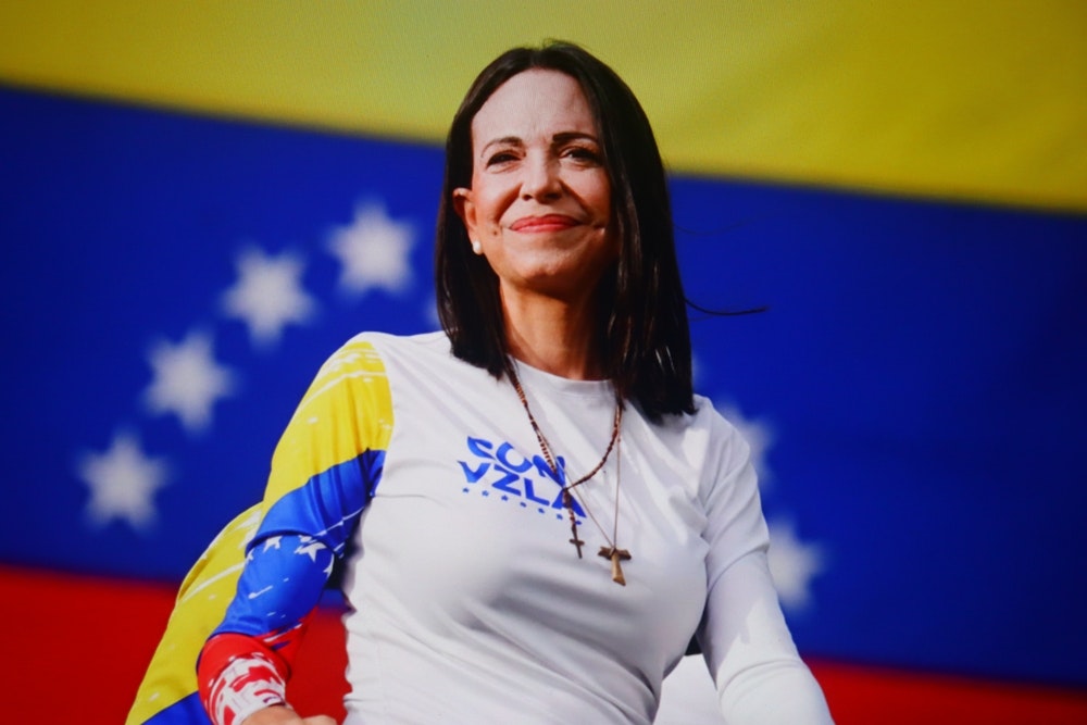 Marina Corina Machado stands in front of a Venezuelan flag
